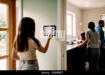 Girl using smart home app on digital tablet while standing near doorway Stock Photo