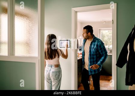 Father looking at daughter using home automation while standing by doorway Stock Photo