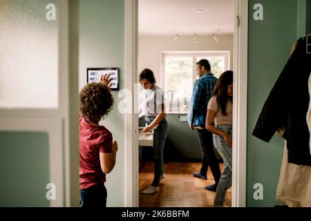 Boy using digital tablet while family in kitchen at home Stock Photo