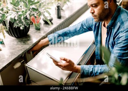 Man checking temperature of radiator through mobile phone at home Stock Photo
