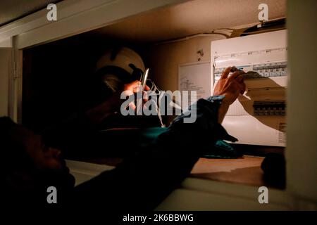 Man turning on switch from fuse box using smart phone torch during blackout Stock Photo