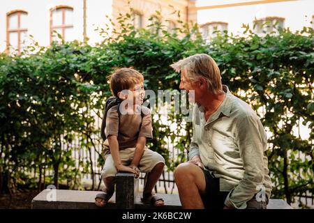 Grandson talking to grandfather while sitting on bench Stock Photo