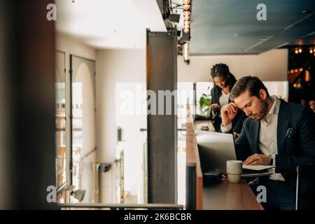 Young male entrepreneur with laptop sitting in hotel Stock Photo