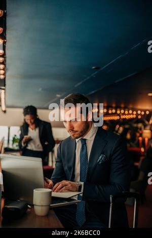 Young businessman using laptop while sitting in hotel lounge Stock Photo