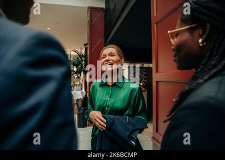 Smiling mature businesswoman talking with male and female colleagues in hotel Stock Photo