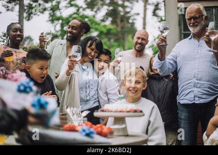 Multi-generation family cheering for boy during birthday celebration Stock Photo