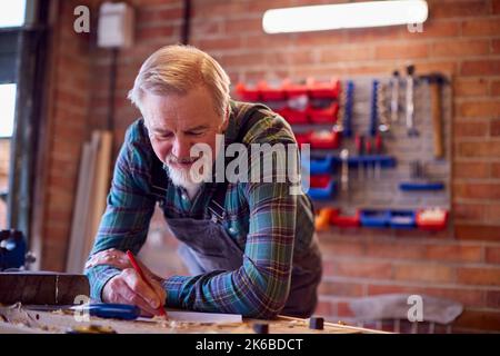 Senior Male Carpenter In Garage Workshop Sketching Out Design On Paper Stock Photo