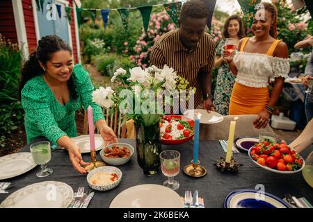 Male and female friends setting up table during garden party Stock Photo