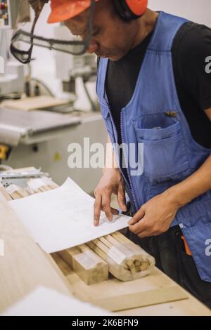 Carpenter worker reading blueprint while working in warehouse Stock Photo