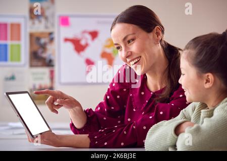 Teacher And Female Student In School Classroom Using Digital Table Together Stock Photo