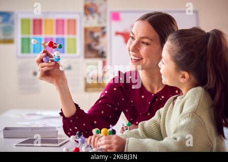 Teacher And Female Student In School Science Class Studying Molecular Model Stock Photo
