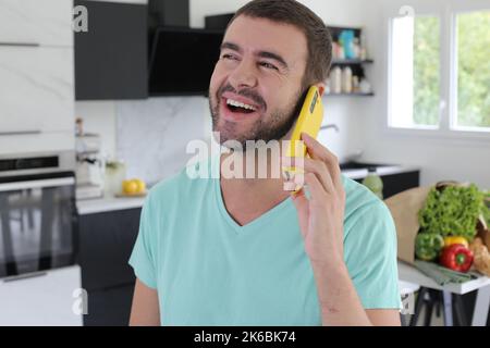 Handsome man calling from his kitchen Stock Photo