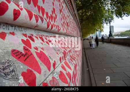 London, UK. 12th October, 2022. Red painted hearts in memory of the thousands who have died from Covid-19 painted on The National Covid Memorial Wall next to the River Thames in London. The number of people dying within 28 days of testing postive for Covid-19 is sadly on the increase again. Credit: Maureen McLean/Alamy Live News Stock Photo