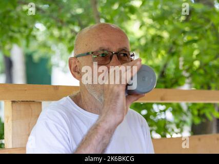 Happy senior man drinking water from bottle after exercise outdoor Stock Photo