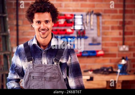 Portrait Of Man Wearing Overalls In Garage Workshop At Home Stock Photo
