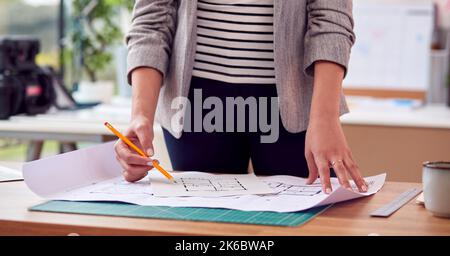 Close Up Of Female Architect Standing Working In Office Studying Plans For New Building Stock Photo