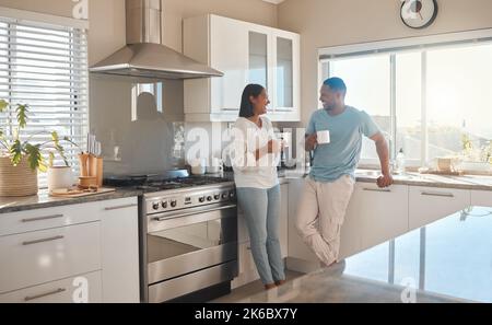 Mornings, coffee and good company. a couple drinking coffee and talking while standing in their kitchen. Stock Photo