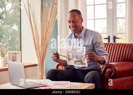 Mature Male Architect Or Interior Designer Working From Home Having Meeting Via Video Call Stock Photo