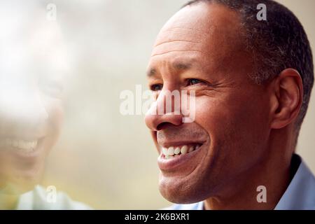 Head And Shoulders Portrait Of Mature Man Or Businessman Standing By Window In Office Or At Home Stock Photo
