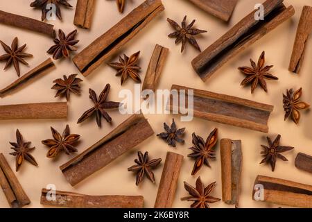 background with cinnamon sticks and anise stars on a beige background, cozy food, spicy trendy background. Stock Photo