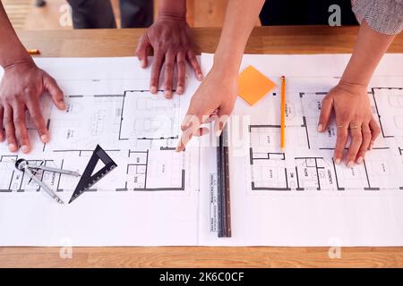 Close Up Male And Female Architects Working In Office Looking At Plans For New Building On Desk Stock Photo