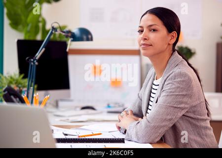 Female Architect Working In Office At Desk Working On Plans For New Building Stock Photo