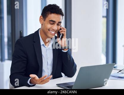 Lets negotiate a deal then. a young businessman talking on a cellphone while working on a laptop in an office. Stock Photo