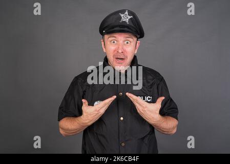 Frustrated Caucasian man wearing police uniform costume against gray studio background Stock Photo