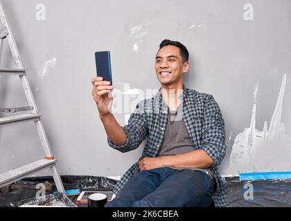 A young Asian man takes a selfie while busy with home improvement DIY project Stock Photo