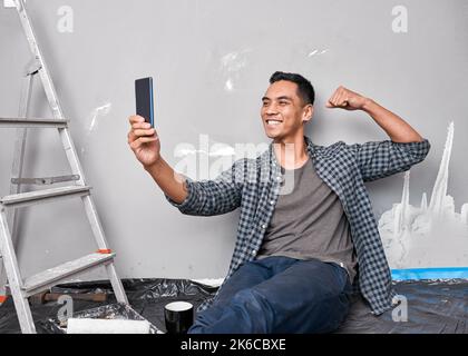 A young Asian man takes a selfie while busy with home improvement DIY project Stock Photo