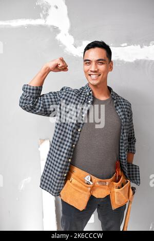An attractive young Asian man poses with strong arm while doing home DIY work Stock Photo