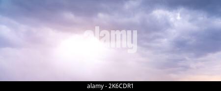 The sun shines faintly through the gray and gloomy clouds Stock Photo
