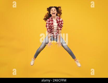Amazed teenager. Happiness, activity and child. Teenager girl jumping on isolated background. Full length, energetic little girl jumping in air, child Stock Photo