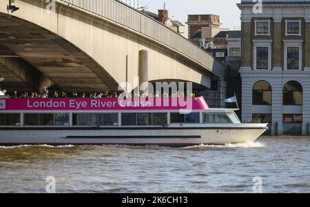 The London Eye river cruise boat travels down the Thames under London Bridge London UK. Stock Photo