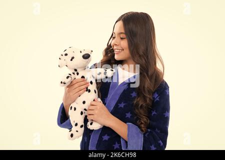 Teen girl feeling relaxed in pajamas, good morning. Teenage girl embracing toy. Childhood, toys and kids. Cute teen girl cuddling favorite fluffy toy Stock Photo