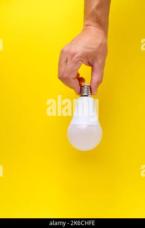 LED eco light bulb in hand on yellow background Stock Photo