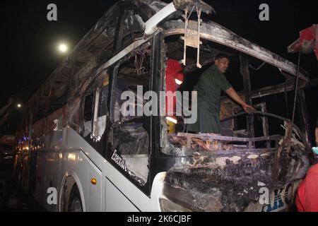 Islamabad, Pakistan. 13th Oct, 2022. Rescuers examine a burnt passenger bus in Jamshoro district of Sindh province, Pakistan, Oct. 13, 2022. At least 18 people, including eight children, were killed and 28 others injured on Wednesday night after a passenger bus caught fire in Pakistan's southern Jamshoro district, police said on Thursday. Credit: Str/Xinhua/Alamy Live News Stock Photo