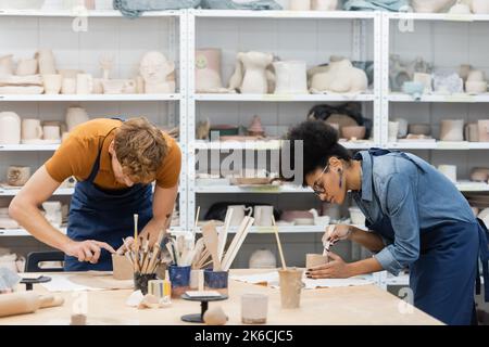 multiethnic woman and man shaping clay cups during pottery class,stock image Stock Photo