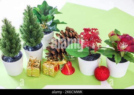 Christmas decor, pine tree and other plants, gold wrapped presents, shiny red bell, and red bauble, on festive green paper Stock Photo