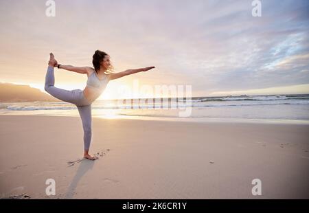 My body is my temple. a young woman practicing yoga on the beach. Stock Photo