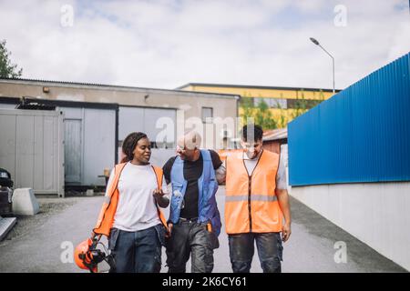 Female construction worker talking with male colleagues while walking on road Stock Photo