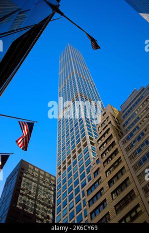 New York, NY, USA - Oct 13, 2022: 432 Park Ave supertall condominium as viewed from the ground looking towards sky with a sunlit USA flag at ground le Stock Photo