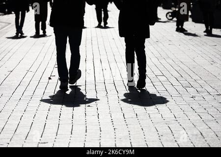 Silhouettes and shadows of people on the street. Crowd walking down on sidewalk, concept of society and population Stock Photo