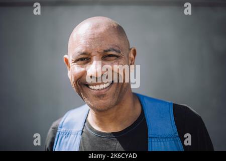 Portrait of happy bald construction worker against wall Stock Photo