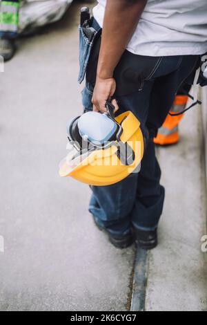 Low section of female construction worker with hardhat at site Stock Photo