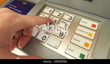 ATM machine and close-up man hand pushing on the pin number button to withdraw the money credit. Stock Photo