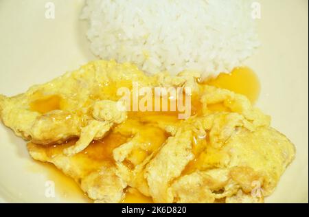 crispy Thai egg omelet stuffed chop pork dressing chili sauce topping on plain rice in white background Stock Photo