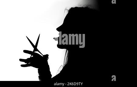 A female silhouette holding scissors in black and white Stock Photo