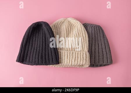 Top view of wool knitted hats on soft pink background. Handmade knitted clothes, winter close concept Stock Photo
