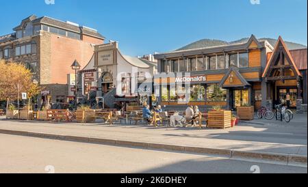 Banff, Alberta, Canada – October 07, 2022:  People dine at table on the sidewalk outside of McDonald’s Stock Photo